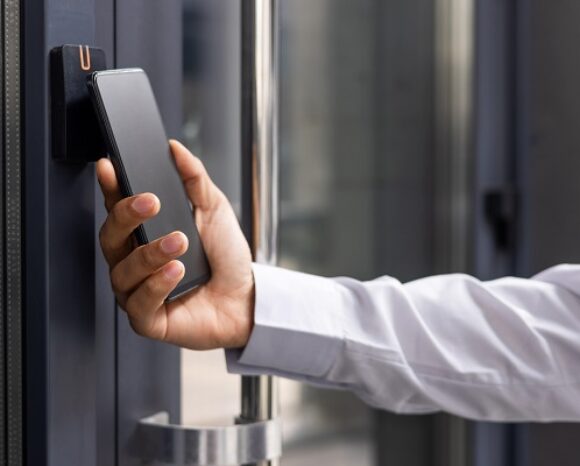 Hand man closely with the phone, the businessman uses the application on the smartphone to remove the door opening of the house, office.