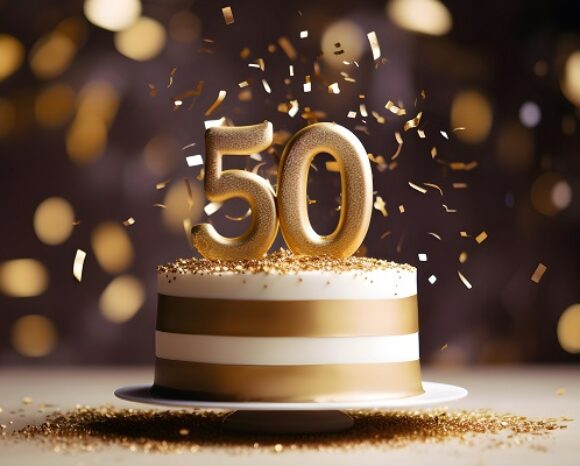 White and golden cake with number 50 on a table decorated for a party celebration