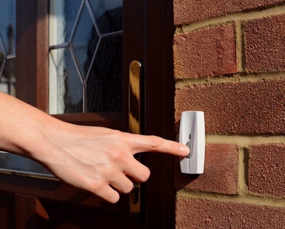 Woman extends her hand to ring doorbell
