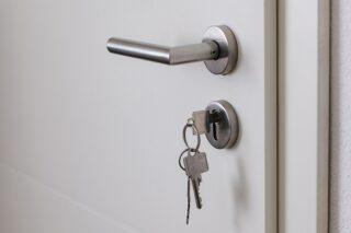Geschlossene Tür mit Schlüssel im Schloss. Weiße Tür und Metallgriff