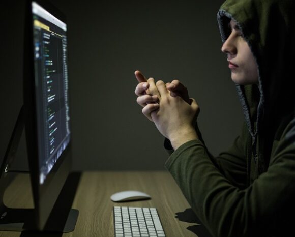 Mann in Kapuzenpullover postet in Online-Chatroom.