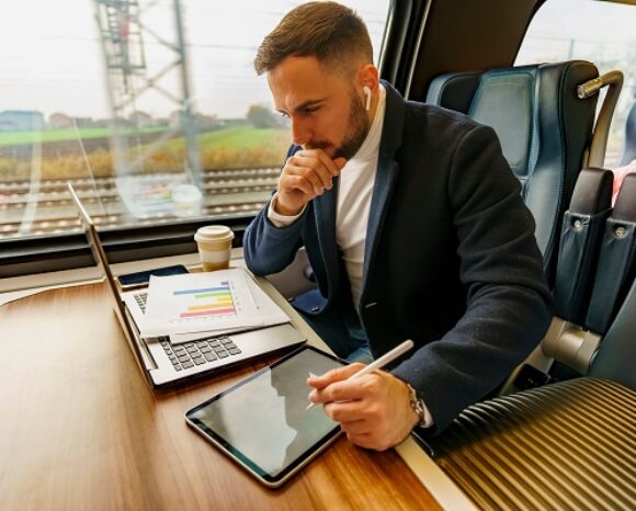 Ultra mobiles Arbeiten, Geschäftsmann pendelt mit dem Zug und arbeitet auf seinem Laptop mobil.