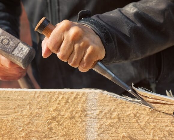 Mann bearbeitet Holzplatte mit Hammer