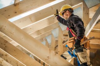 Mann arbeitet alleine an einem Holzdach