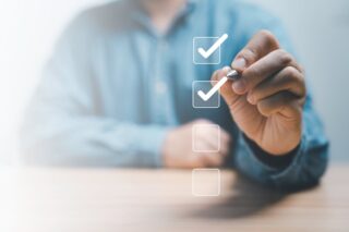 Geschäftsmann benutzt Stift, um das richtige Häkchen im Kontrollkästchen zu setzen