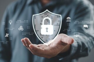 Eine Person demonstriert digitale Sicherheit mit einer Handgeste, indem sie in einem technologieorientierten Umfeld ein Schlosssymbol auf einem Schild zeigt.