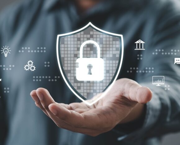 Eine Person demonstriert digitale Sicherheit mit einer Handgeste, indem sie in einem technologieorientierten Umfeld ein Schlosssymbol auf einem Schild zeigt.