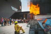 Live-Demonstration eines Brandversuchs im Außenbereich der FeuerTrutz mit Zuschauergruppe und Einsatzkraft.