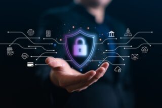 Hand eines Geschäftsmannes, der ein virtuelles Schild mit Vorhängeschloss und Netzwerksymbolen hält.