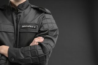 Männlicher Sicherheitsbeamter in Uniform vor dunklem Hintergrund