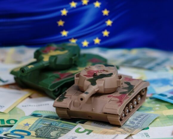 2 Miniatur Panzer auf Euro-Scheinen mit EU-Flagge im Hintergrund