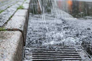 Städtisches Regenwasser, das bei starkem Regen in eine Drainage fliesst