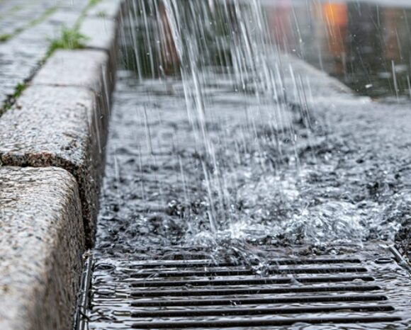 Städtisches Regenwasser, das bei starkem Regen in eine Drainage fliesst